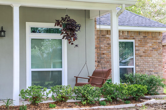 A Wooden Porch Swing On The Front Patio Of An Acadian Style House In Louisiana