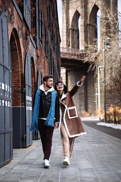 Happy man and woman walking on Manhattan streets over Brooklyn bridge background. Cheerful couple of tourist in empty autumn city in New York. Tourists in nyc enjoy downtown landmarks. Morning NY walk