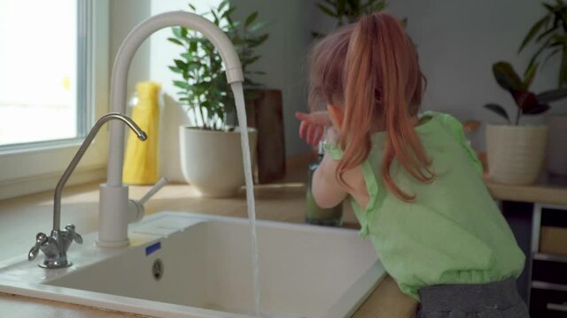 Little girl in kitchen wash hands. Child Lathered with liquid soap to protect viruses and microbes. Personal kids hygiene at home. Careful use of water. Come and go away. sink foam skin health