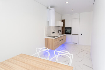 Absolutely stunning kitchen interior in light colors with blue lighting, wood countertops and marble tiles.