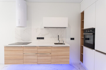 Absolutely stunning kitchen interior in light colors with blue lighting, wood countertops and marble tiles.