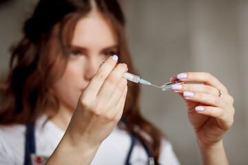 Woman-doctor removes protection cap from syringe. Using syringe concept. Close-up.