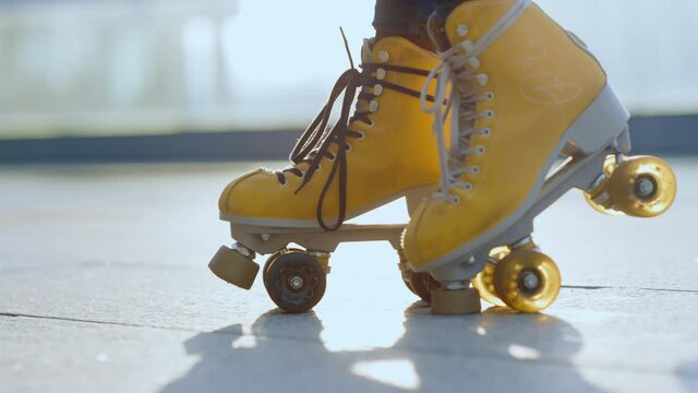 Unknown roller skater staying outside. Woman feet riding rollerblades outdoor.