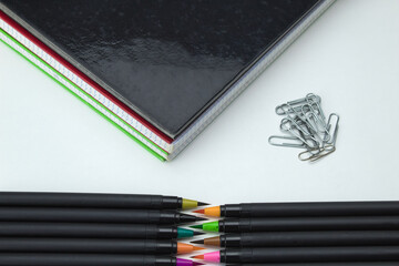 set of school tools with colored self-tips pens, clips and notebooks on white background