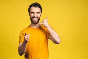 A photo of good-looking young bearded man in casual isolated on yellow background making a gesture 