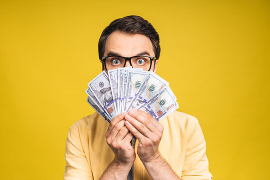 Image of shocked excited young handsome bearded man posing isolated over yellow wall background holding money make winner gesture.