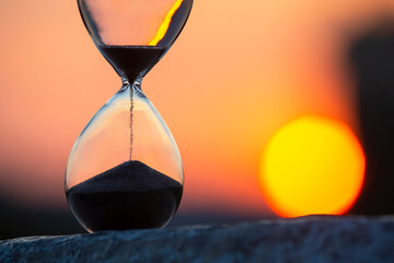 Hourglass counts the length of time against the background of the evening sun