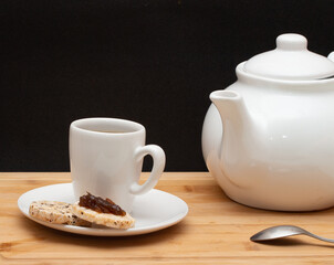  a cup of coffe surounded by  a coffee pot