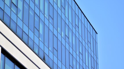 Obraz premium Futuristic facade of a modern office building clad in glass. Glass cladding panels and windows of modern building. An office building with geometry and perspective.