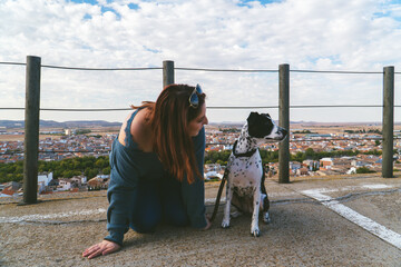 Mujer arrodillada en el suelo junto a su perro blanco y negro, entrenando a un perro, chica joven...