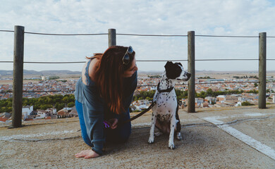 Mujer arrodillada en el suelo junto a su perro blanco y negro, entrenando a un perro, chica joven...
