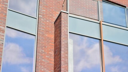 Futuristic facade of a modern office building clad in glass. Glass cladding panels and windows of modern building. An office building with geometry and perspective.