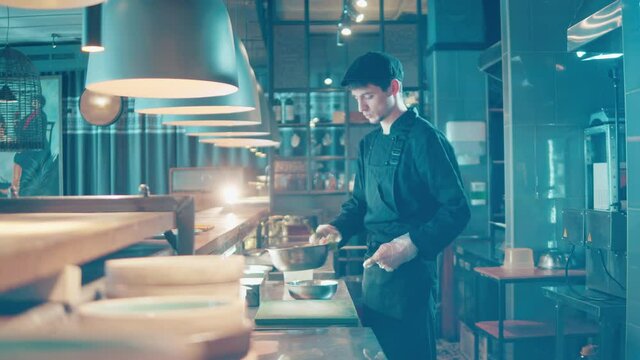 Male chef is tossing salad in a bowl