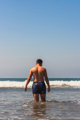 Fototapeta na wymiar Young latino man entering the sea summer