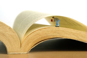 Miniature people toy figure photography. A men searching a data on opened book
