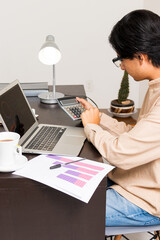 Young man working in an office doing calculations on investment