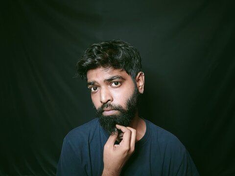 indian guy with beard and piercings wearing black t-shirt unisexual written on it with fun facial expressions