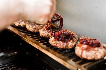 Rindfleisch Burger für Hamburger auf dem Grill mit Käse und Zwiebeln überbacken