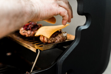 Rindfleisch Burger für Hamburger auf dem Grill mit Käse und Zwiebeln überbacken
