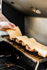 Rindfleisch Burger für Hamburger auf dem Grill mit Käse und Zwiebeln überbacken