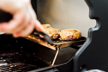 Rindfleisch Burger für Hamburger auf dem Grill mit Käse und Zwiebeln überbacken