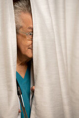 Photo of a doctor hiding in his office behind the curtains