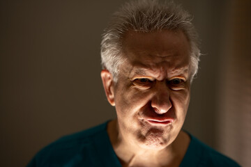 Obraz premium Old man making a angry face lit from below