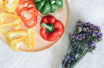 Sweet Pepper Cutting Sliced Preparation for Cooking. Raw Variety Red, Green, Yellow Sweet Peppers Slicing Chopped in Wooden Bowl on Kitchen Table. Raw Organic Sweet Pepper Ready to Eat