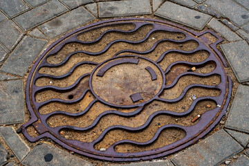 Metal covers of sewer manholes on city roads close-up.