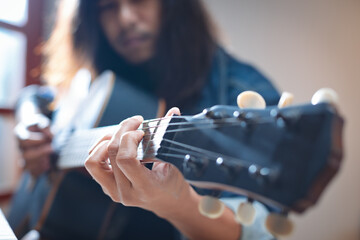 Close up on hand of asian musician who have long hair is playing acoustic guitar and change chord...