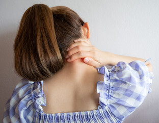 Fototapeta premium Rear view of woman having neck pain from strain, injury or office syndrome. Neck pain caused from poor posture from work or overuse.