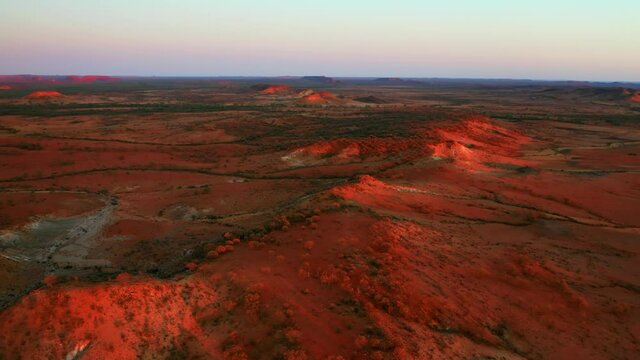 A Vehicle Traveling At The Road With Rugged Grassland And Red Desert In Alice Springs, Australia. aerial, orbit