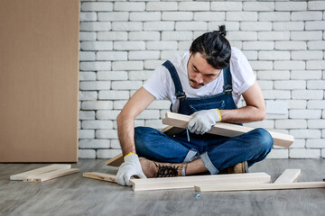 Young hipster Asian man working as handyman, assembling wood table with equipments, concept for...