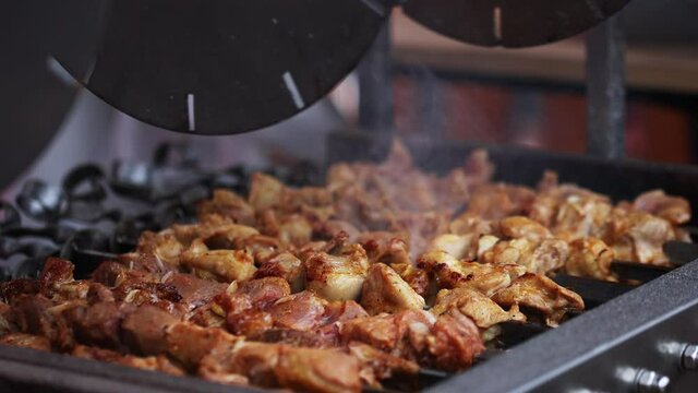 delicious barbecue meat shashlik beaf pork slices in rolling grilled in skewers on a fire. outdoor street food concept