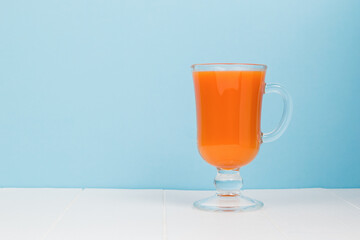 A glass of smoothies on a white table on a blue background.