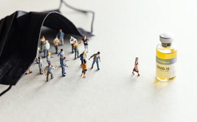 Group of people (figurine) standing and walking to the Coronavirus COVID-19 vaccine for injection .Coronavirus vaccine, population immunization campaign concept background.
