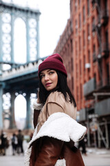 Portrait of young woman in trendy outfit with cherry lipstick over New York downtown background....