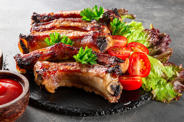  Baked pork ribs with vegetables, mustard and ketchup on gray background close up