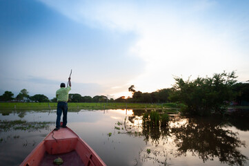 Man rowing a bongo in the Apure river at sunset