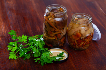 Mix of chopped marinated forest mushrooms in glass jar, homemade preserves