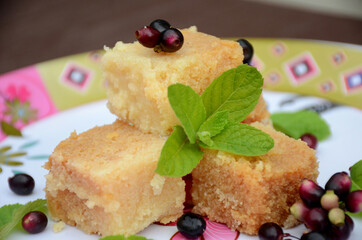 closeup brown color milk cake sweet with black j amble and green mint over out of focus white brown background.