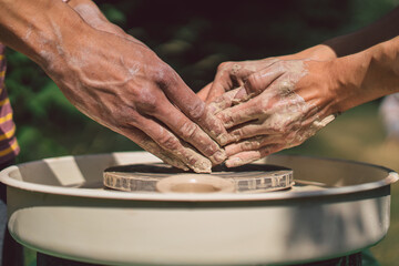 Potter making a clay object on pottery wheel in outdoors. Craftsman moulding clay with hands on pottery wheel