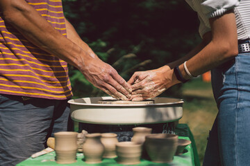 Potter making a clay object on pottery wheel in outdoors. Craftsman moulding clay with hands on pottery wheel