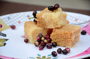 closeup brown color milk cake sweet with black j amble over out of focus white brown background.