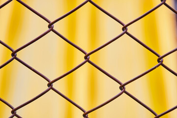 closeup a steel fence with yellow background