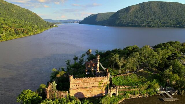 Aerial drone footage of an abandoned castle on a small island. This is Bannerman's castle on Pollepel island in New York's Hudson River Valley during summer in America.