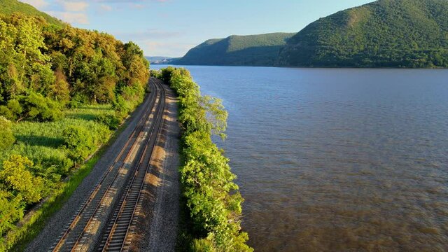Aerial drone footage of the metro north Hudson Line train tracks during summer next to the Hudson river between beacon and cold spring, new york, usa