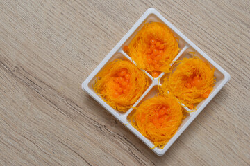 Foi Thong sweets in a plastic box on a wooden table