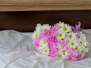 Nice wedding bouquet with pink and white chrysanthemums lie on bed in the light room at the morning. Bed pastel composition with flowers. Horizontal, copy space