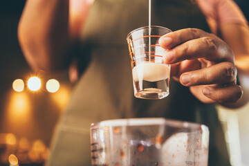 professional barista make a fresh drink with tea and milk on cup, beverage tasty bar cafe, hand holding milk latte in coffee shop or food restaurant, bartender working in cafeteria uniform